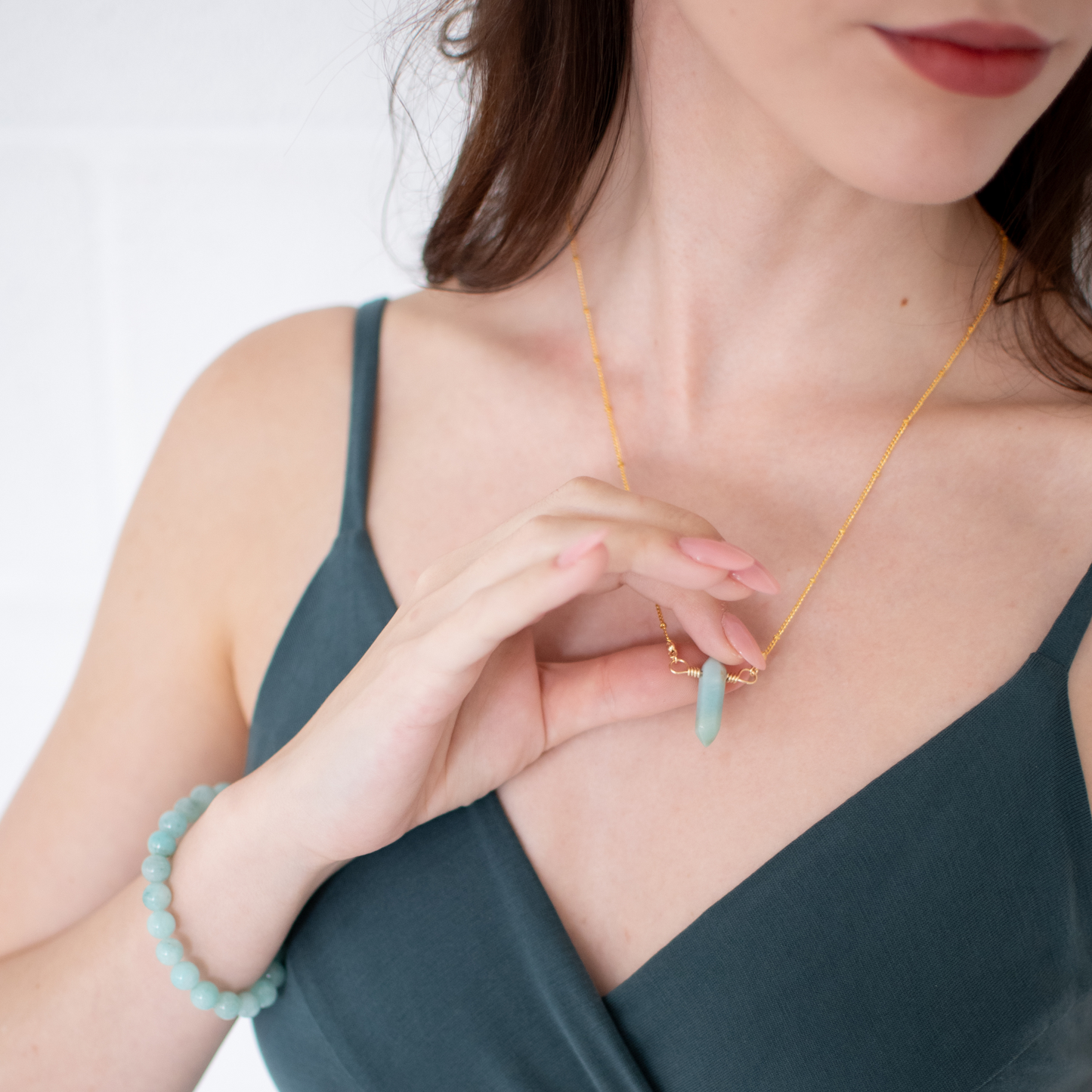 Woman wearing a gold necklace with blue beads against a white background