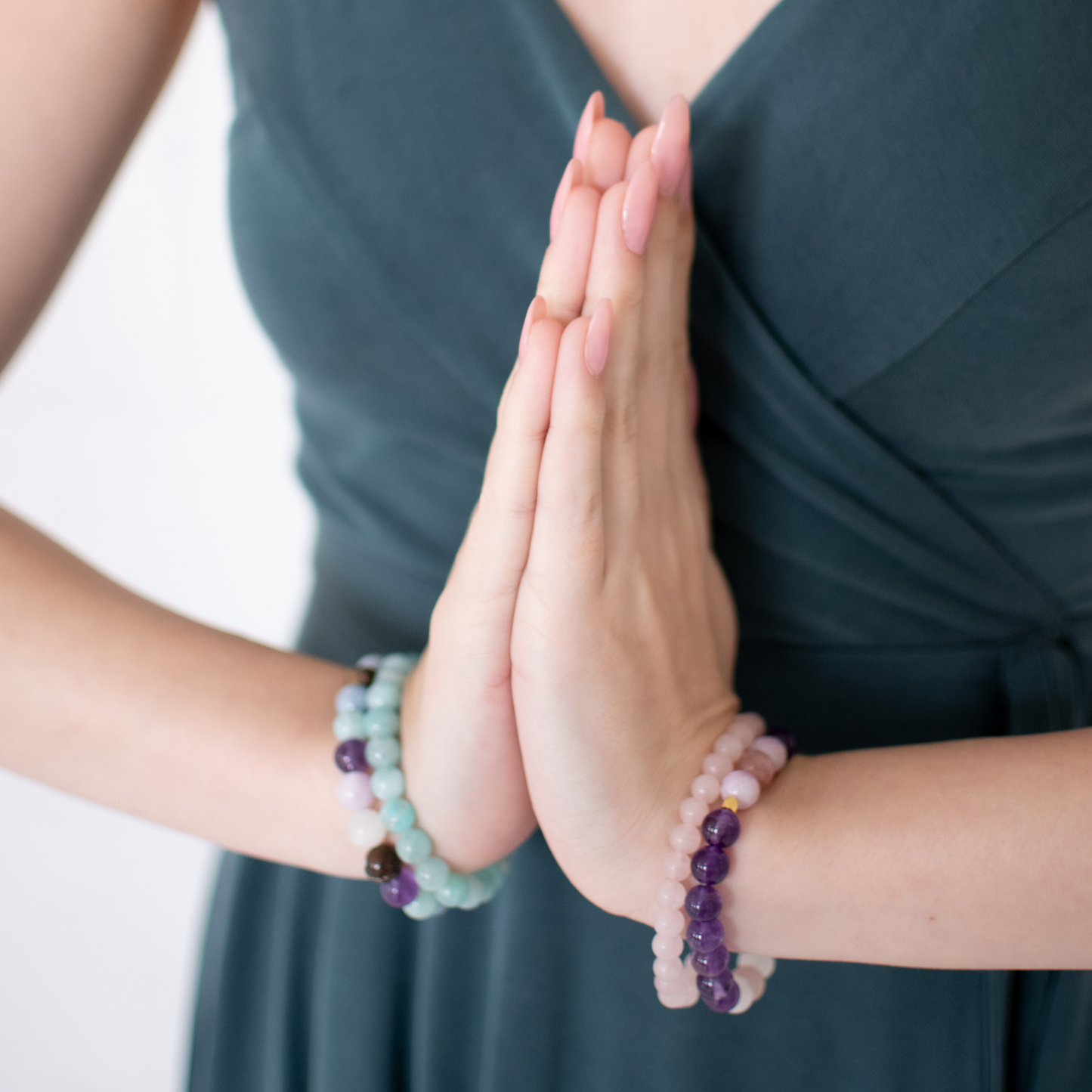 Two hands with beaded bracelets on a blurred background