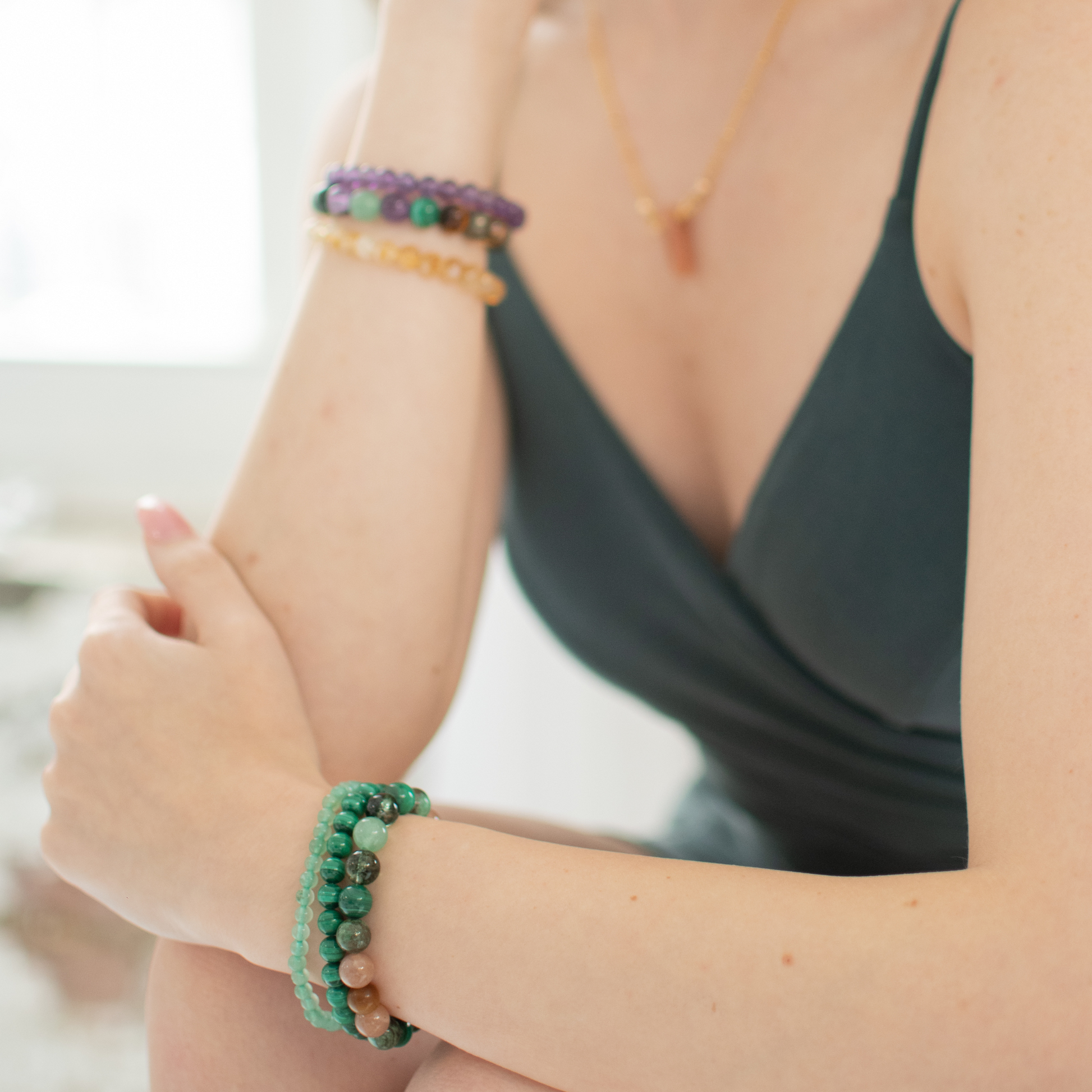 Person wearing multiple bracelets on their wrist with a blurred background