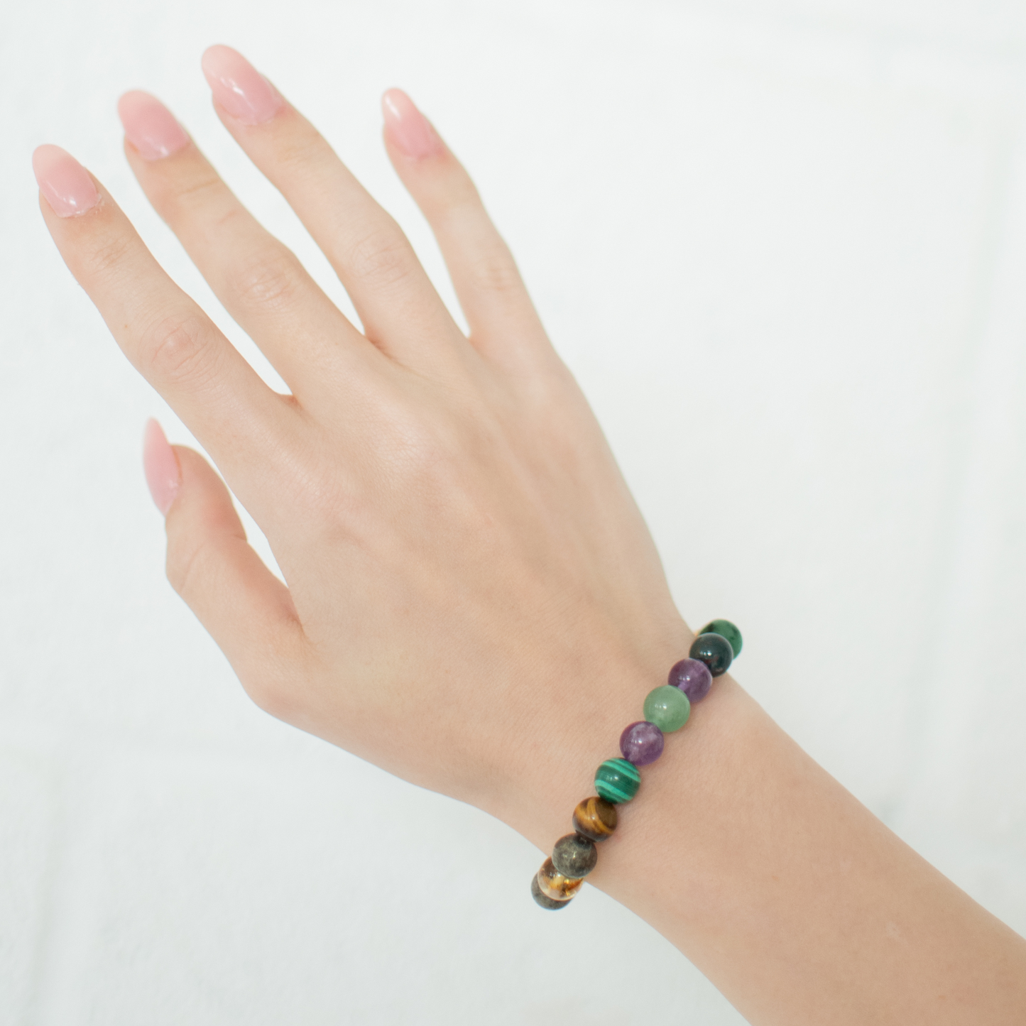 Multicolored beaded bracelet on a hand against a white background