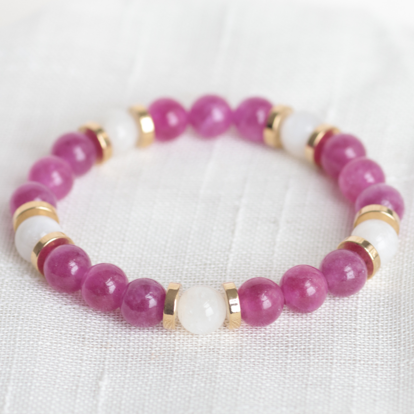 Beaded bracelet with pink and white beads on a light fabric background