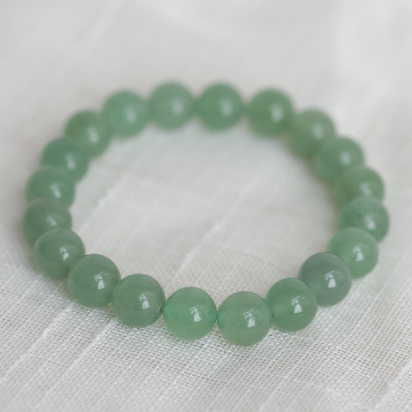 Green beaded bracelet on a white fabric background