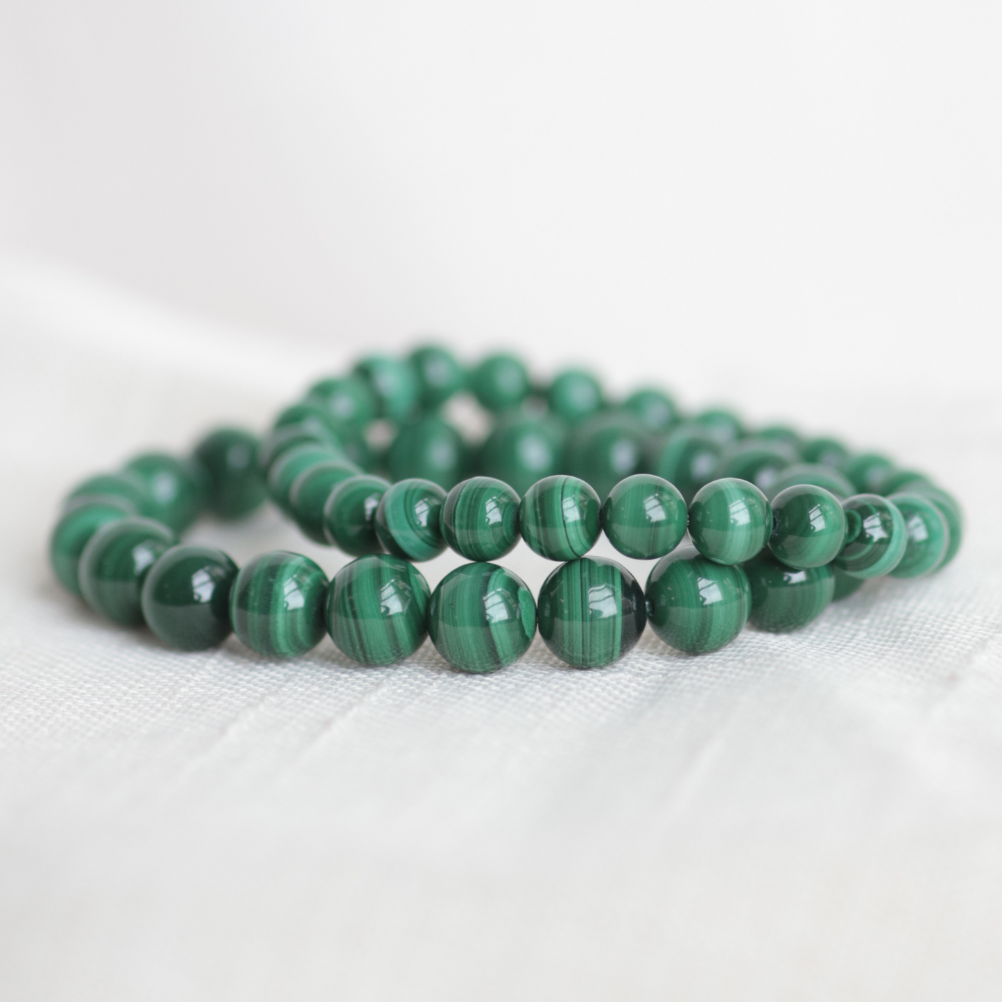 Green beaded bracelets on a white fabric background