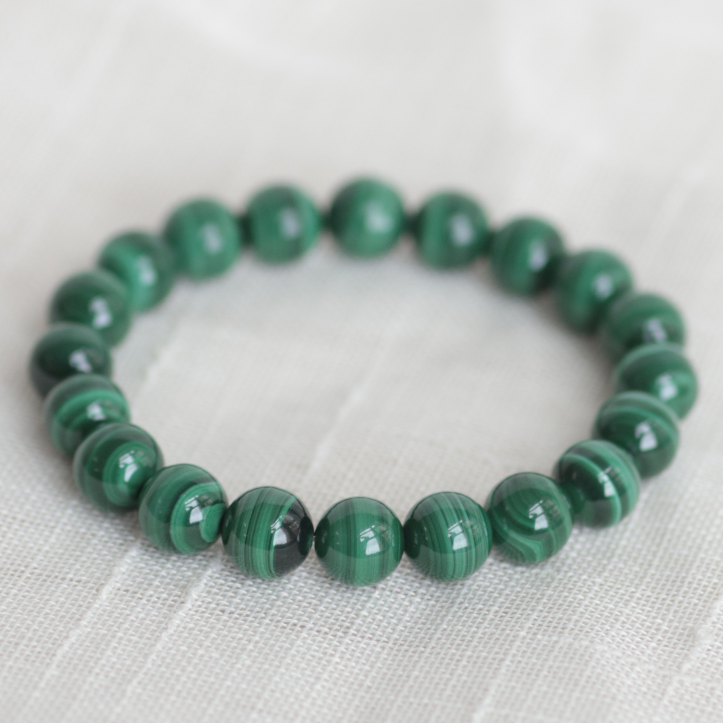Green beaded bracelet on a light fabric background