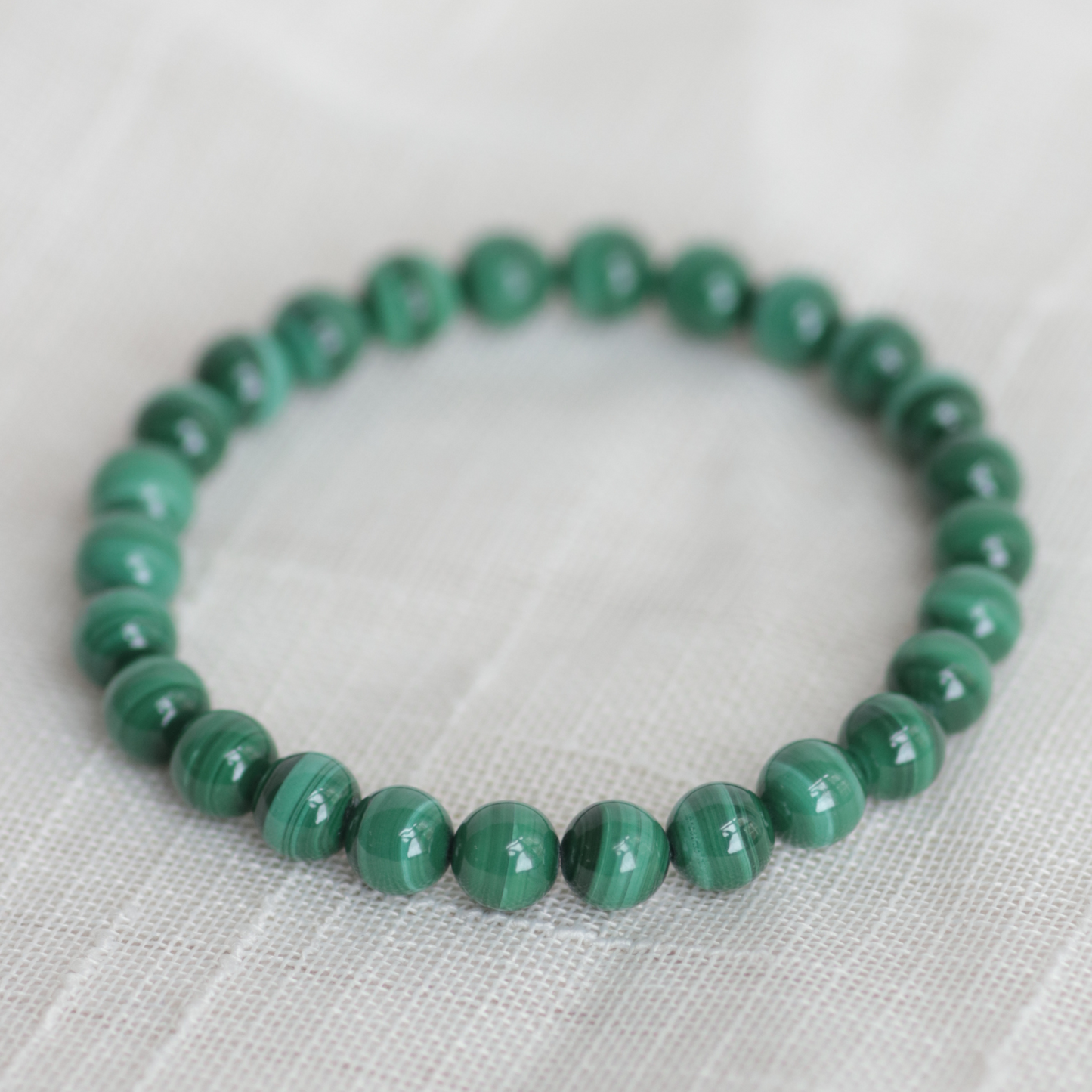 Green beaded bracelet on a light fabric background
