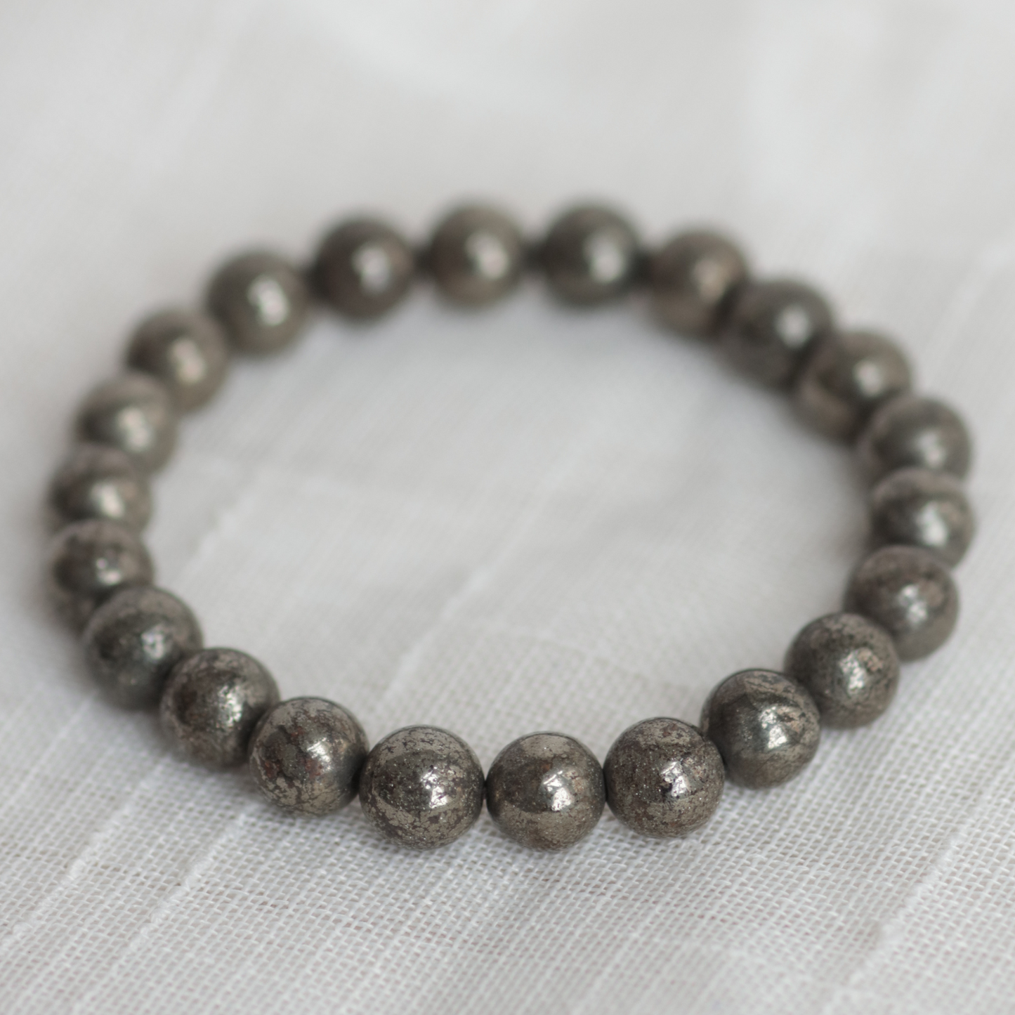 Silver beaded bracelet on a light fabric background